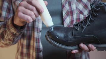 Man prepares black suede boots before fall and winter by applying a protective and nourishing suede cream while holding boot in his hands. Topic winter shoe care. Theme maintenance of autumn boots. video