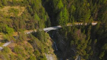 Luftaufnahme Schurpfen Wasserfall. Aerial view of crooked waterfall Schurpfen and bridge in gorge with forested mountain and canyon near Sylvensteinspeicher in Lenggries. Drone view falls and bridge. video