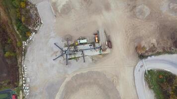 Aerial view of functioning sand quarry in industrial zone in Germany. Heavy machinery operates across sprawling sandy landscape, shrouded in autumn fog, emphasizing an active worksite atmosphere. video