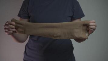 A woman puts on a compression sleeve on her arm to support vein health and prevent thrombosis. Compression helps improve circulation, reducing the risk of blood clots, varicose veins, and embolism. video