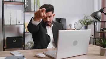 Business man working on office laptop pointing to camera looking with happy expression making choice video