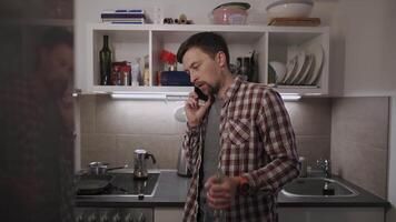 A young, sad, and depressed man stands in his kitchen, holding a bottle of wine. Battling personal and work problems, he talks on the phone, facing alcoholism, loneliness, and emotional despair video