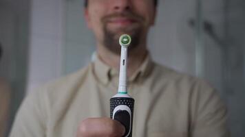 Close-up of man holding black electric toothbrush, activating and deactivating it. The image highlights the advanced ultrasonic technology, emphasizing oral hygiene and modern dental care routines. video