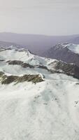 large snow patch left over on the volcanic rock field of a mountain in summer video