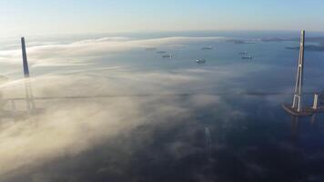 Aerial view of a huge cable bridge over a foggy strait at dawn video