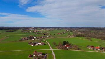 Small village in Bavaria, Germany on sunny spring day with road and green fields all around. Aerial view of little farming community with organic agricultural fields in bayern. Drone view of farmland. video