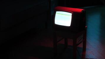 Old analog television set displaying static noise in dark room video