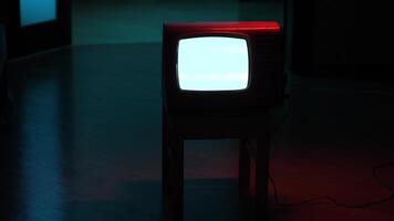 Old analog television set displaying static noise in dark room video