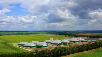 Innovative biogas farm. Biogas power plants on green field under beautiful sky. The agricultural and greenhouse complex is equipped with its own biogas production. Aerial view. video