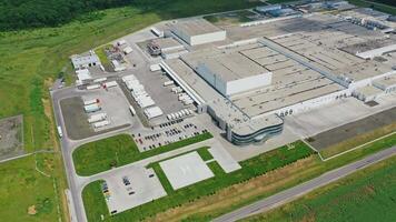 White factory on field. Modern industrial plant with parking spaces for trucks and cars among green nature. Aerial view. video