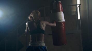 An athlete practicing her boxing punching technique, delivering accurate and powerful punches on the punching bag. Slow motion video
