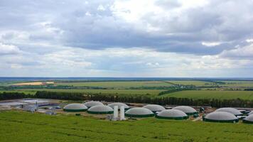 innovativ Komplex von Biogas Produktion. Panorama- Aussicht von Biogas Pflanze unter Grün Felder. Lager Panzer mit Biomasse. Antenne Sicht. Kamera ziehen um zurück. video