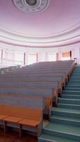Beautiful conference hall with empty seats. Modern auditorium with wooden desks for lectures. Spacious university classroom without people. Vertical video