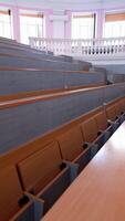 Rows of long desks in conference hall. Empty auditorium in the modern educational center. Wooden tables without students in large comfortable classroom. Vertical video