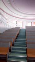 Modern auditorium with stairs. Many rows of wooden desks rising up in the conference hall. Spacious classroom for lectures in the university. Vertical video