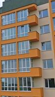 Construction of a modern building in the city. Facade of multistory apartment house with plastic windows in the city. Building of a new architecture concept Vertical video