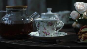 Teapot with brewed black tea and tea set on table. Table set for tea with fresh pastries. video