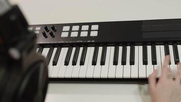 Close up view of a musician's hand skillfully playing an electronic keyboard in a music studio, surrounded by headphones, actively creating and composing new melodies video