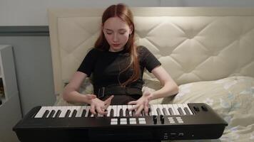 Young composer warming up her hands, preparing to play a midi keyboard resting on the bed in her cozy bedroom, embracing creativity and inspiration in a relaxed atmosphere video
