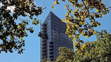 Construction work on a skyscraper. Construction elevator goes up, Modern Glass Building Framed by Trees video