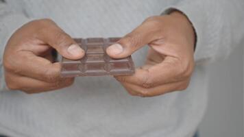 An individual is holding a square chocolate bar firmly with both hands video