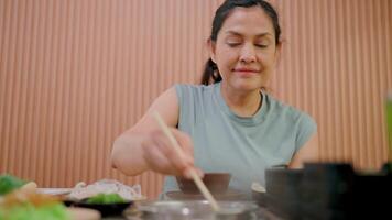 saboreando el momento,un mujer disfruta un delicioso comida, su ojos cerrado en puro contentamiento. el vapor desde el plato agrega un toque de calor a el imagen, destacando el sencillo placeres de vida. video