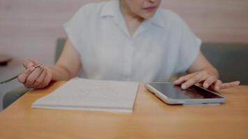 Focused Woman Working. A close-up shot of a woman concentrating intently on her work, using both a tablet and a notepad. The image conveys focus, productivity, and diligence. video
