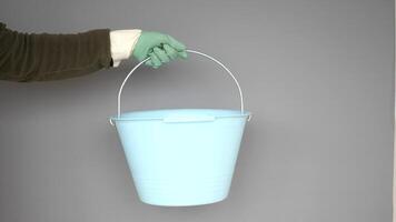 A blue bucket with a handle being held by a gloved hand in a precise manner video