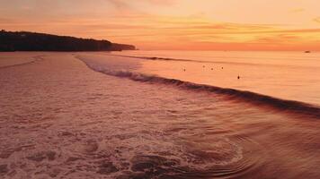 Ocean view with surfing waves on Impossibles beach surf spot with evening warm sunlight, drone view video