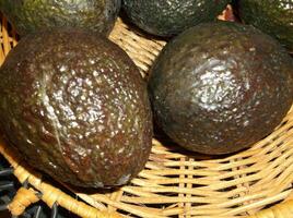 A basket of ripe avocados sitting on a table photo