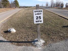 A speed limit sign on a road in the subdivision. photo
