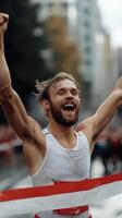 A runner joyfully crosses the finish line with arms raised in celebration. The scene captures the excitement of victory in an urban marathon setting, creating a vibrant atmosphere photo