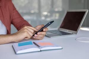 Man hands using phone inside office at workplace, man typing message on using online app to view investment reports. photo