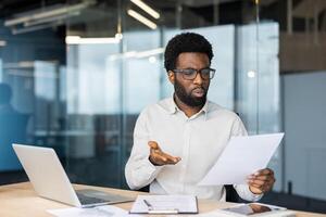 A financier accountant holds a report in his hands, a man is dissatisfied with the results of his activities. A man works inside the office, checks documents, bills and payments. photo