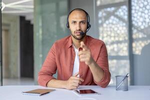 Person wearing a headset communicating via call while working in a contemporary workspace. Related to remote work, communication, and modern technology. photo