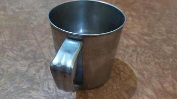 a metal mug with a handle on a table, photo