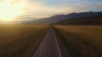 AERIAL. Empty road with fields in a valley surrounded by mountains at sunset video