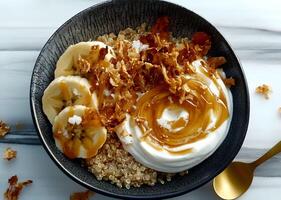 Delicious quinoa bowl topped with creamy yogurt, slices of banana, crunchy toppings, and drizzled with golden syrup for a nutritious breakfast treat photo
