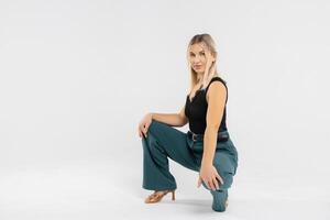 Confident businesswoman crouching in studio, showcasing modern office attire photo