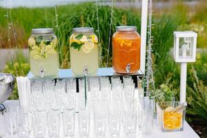 Lemonade and orange juice in glass jars serving guests at an outdoor party photo
