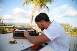 Man Using Tool To Fix And Tune Accordion photo