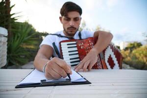 Man Studying Accordion And Watching On The Paper photo