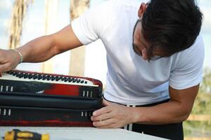 Man Using Tool To Fix And Tune Accordion photo