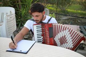 Man Studying Accordion And Watching On The Paper photo