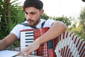 Man Studying Accordion And Watching On The Paper photo