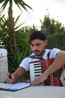 Man Studying Accordion And Watching On The Paper photo