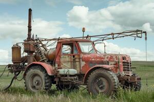 Old rusty broken tractor for fertilizer with trailer in the field is waiting for repair photo