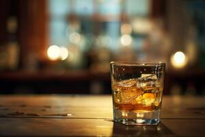 Glass of whisky with ice cubes sitting on bar countertop photo