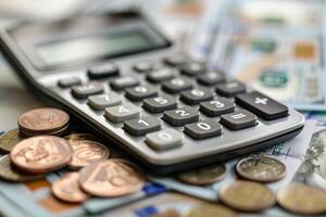 Accountant calculating expenses with calculator on desk with dollar bills and coins photo