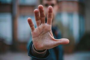 Man making stop sign with hand in front of face photo